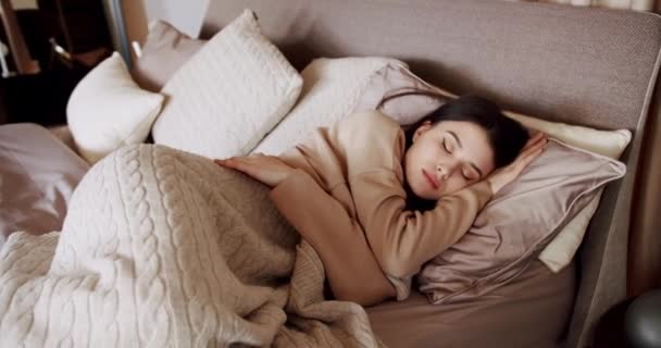 Frau schläft morgens im Bett. Ruhige junge Frau schläft gut im gemütlichen Bett — Stockvideo