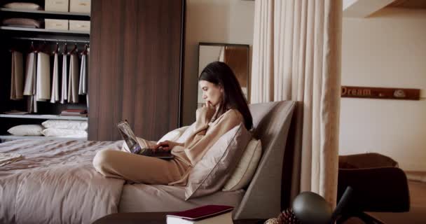 Joven hermosa mujer usando aplicaciones portátiles usar pijama sentado en la cama acogedora — Vídeos de Stock