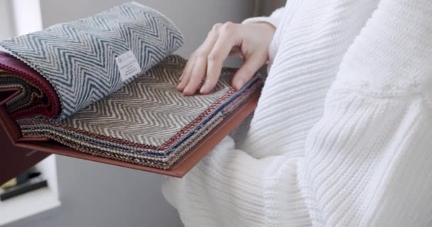 Крупним планом жіночі руки вибирають тканину з кольорової палітри в текстильному шоу-румі . — стокове відео