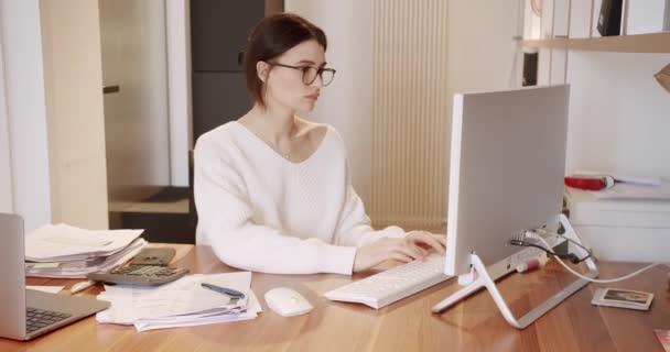 Jonge zakenvrouw in glazen werken in kantoor interieur op de pc op het bureau, typen — Stockvideo