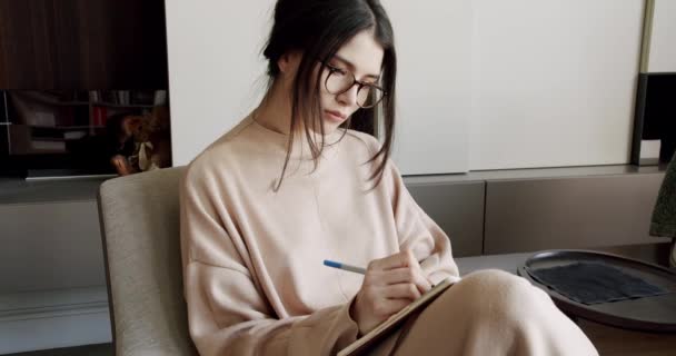 Mujer atractiva escritora independiente está escribiendo su artículo en un cuaderno. — Vídeos de Stock