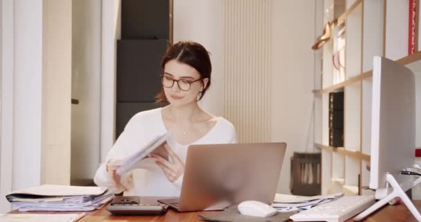 Mooie jonge vrouw werkt op laptop computer terwijl op kantoor. — Stockvideo