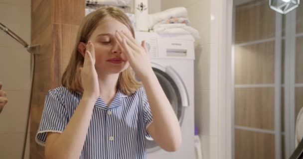 A tinédzser lány gondoskodik a reggelről a fürdőszobában, belenéz a tükörbe. — Stock videók