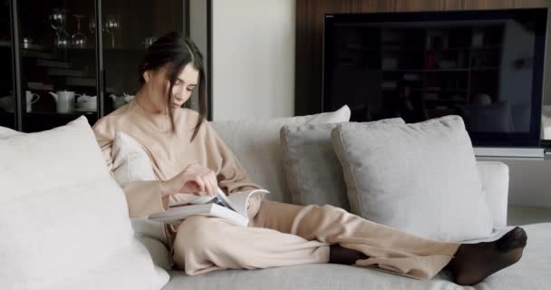 Drömmande kvinna sitta inomhus läsa bok, Njut av mysig lat helg i moderna hem — Stockvideo
