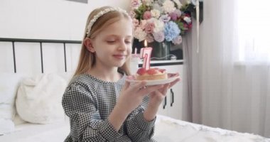 7 yaşında mutlu bir kızın doğum günü partisi ve pastaya mum üflemesi..