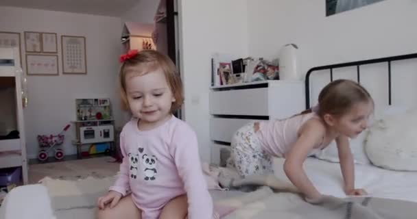 Twee kleine meisjes spelen thuis, springen van vreugde en glimlachen mooi. — Stockvideo