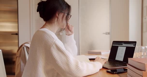Όμορφη νεαρή γυναίκα σε γυαλιά Λειτουργεί σε φορητό υπολογιστή, ενώ στο γραφείο. — Αρχείο Βίντεο
