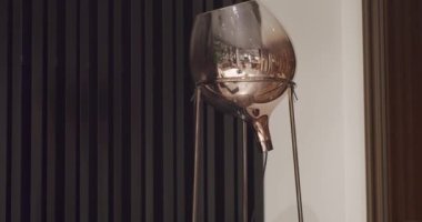 Modern siyah çizgili pencerenin yanındaki kahverengi minimalist yuvarlak lamba.