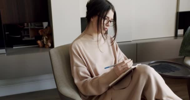 Mujer atractiva escritora independiente está escribiendo su artículo en un cuaderno. — Vídeos de Stock