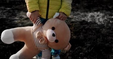 Orphan child in the colors of the Ukrainian flag with a toy bear in Ukraine war