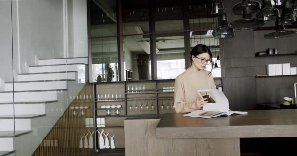 Mulher motivada atraente em óculos desfrutar na sala de cozinha e ler um livro — Vídeo de Stock