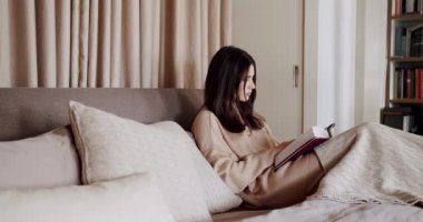 Evde yatakta kitap okuyan bir kadın. Dinlenme ve eğitim kavramları zamanı