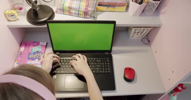 Teenage pige studerer hjemme på laptop med grøn skærm derhjemme. Top visning – Stock-video