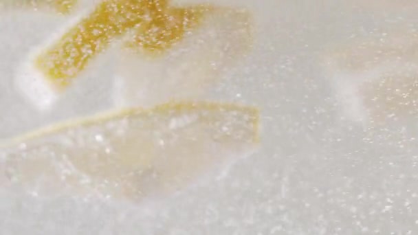 Αργή κίνηση Μακρο πλάνο μιας φέτας λεμονιού σε φυσαλίδες νερού, πίνοντας κρύα λεμονάδα — Αρχείο Βίντεο