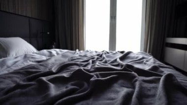 Çift yatak, perdeler, gece masaları ve büyük televizyonlu gerçek bir modern yatak odası. Lüks bir otel ve rahat bir daire. Çağdaş ve şık yatak odası. Minimalist Tasarım Biçimi.