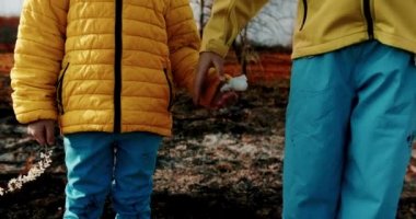 Ukrayna bayrağı renginde giyinmiş küçük kız kardeşler savaş sırasında yanmış bir arka planda el ele tutuşuyorlardı. Ukrayna 'daki savaşı durdurun. Evsiz çocuk. Rus saldırganlığı. Kriz, savaş çatışması