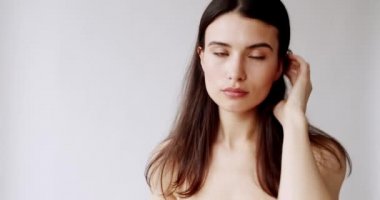 Beyaz arka planda kameraya bakan genç, lüks ve seksi bir kadının yakın plan portresi. Profesyonel mankenin yüzü, kahverengi gözlü makyajcı bayan. Cilt bakımı, kozmetik