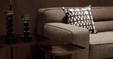 Yastıklı tekstil döşeme kanepesi. Modern apartman güzel bej kanepe modern oturma odasında lamba, halı, masa. Ahşap duvarlı İskandinav iç mimarisi. Modern gri ve bej kumaş kanepe