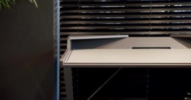 Rahat çalışma odasında minimalist deri koltuklu modern ahşap çalışma masası. Oda palmiyesi dekoru. Minimalist siyah panjurlar. Beauty Interior 'da yatak odası aksesuarı, deri koltuk ve modern masa..