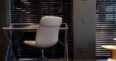 Rahat çalışma odasında minimalist deri koltuklu modern ahşap çalışma masası. Oda palmiyesi dekoru. Minimalist siyah panjurlar. Beauty Interior 'da yatak odası aksesuarı, deri koltuk ve modern masa..