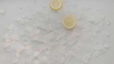 Beyaz arka planda buz küpüyle limon dilimi düşüşü. Limonlu kokteyl, ferahlatıcı limonlu soda, soğuk yaz içeceği. Limonlu soda..