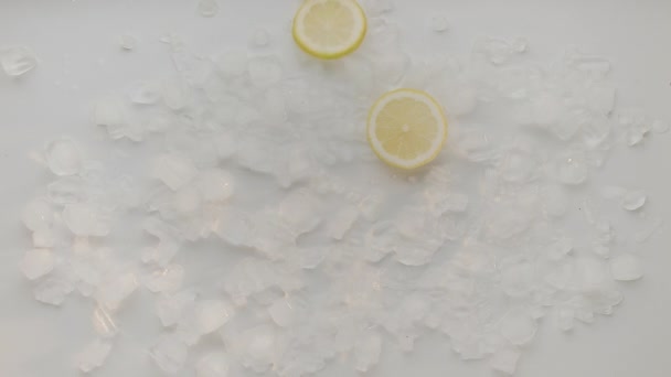 レモンのスライスは白い背景にアイスキューブで落ちます レモンと強壮剤の水と夏のカクテル リフレッシュメントはレモンソーダ 冷たい夏の飲み物を輝きます レモンソーダ飲料 — ストック動画