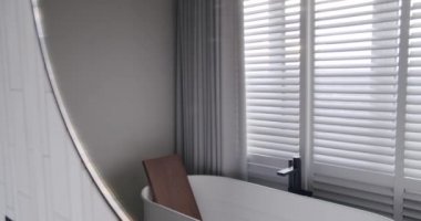 Lüks Banyo İçi, banyo aksesuarları, ayna ve duş başlığı, modern iç mekanda yuvarlak ayna, banyo küveti modern tasarımı olan minimalist iç mimari. Lüks, rahat, beyaz bir daire..