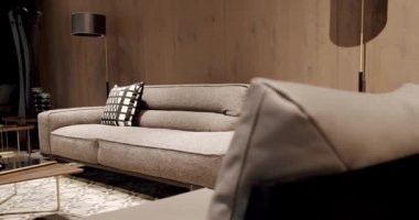 Modern gri ve bej kumaş kanepe. Modern apartman güzel bej kanepe modern oturma odasında lamba, halı, masa. Ahşap duvarlı İskandinav iç mimarisi. Yastıklı tekstil döşeme kanepesi.