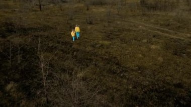 Ukrainian girls in clothes in the colors of the Ukrainian flag on the ground, destroyed and burned. Crisis, peace, stop the aggression. Ukrainian national colors, Sad refugee children.