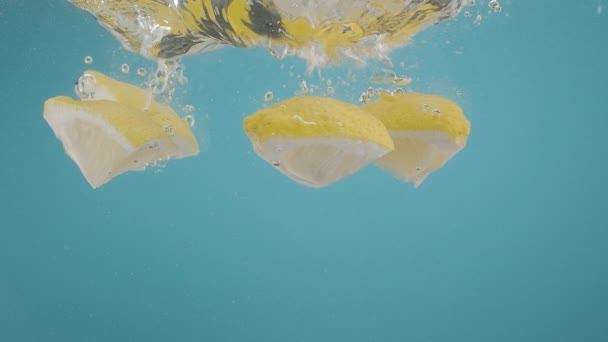 柠檬的缓慢下落会在蓝色背景上被切割成飞溅的水 夏季鸡尾酒配柠檬水和补水 调味柠檬苏打水 夏季冷饮 柠檬苏打水 — 图库视频影像