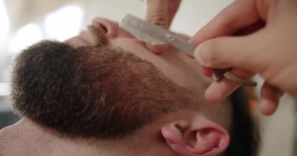 专业理发师用直剃须刀刮胡子 理发店用老式刀片剪胡子 特写帅哥在理发店刮胡子 刮胡子 — 图库视频影像