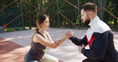 Sportif erkek ve kadın kalçalarının kaslarını ve kalçalarını güçlendirmek için tek ayak üzerinde hamle yapıyorlar. Antrenör erkek, formda kadın egzersizleri yapıyor. Kişisel antrenörle açık hava eğitimi.