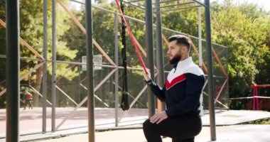 Spor salonu sağlığı konseptin dışında. Antrenör erkek düzeltme egzersizleri lastik bant ile yapıyor. Açık hava sporcusu elastik bantla egzersiz yapıyor. Çekici fitness adamı dışarıda egzersiz yapıyor..