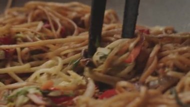 Profesyonel aşçı erişteli sebze kızartıyor. Yemek pişirme süreci çok yakın. Çin eriştesi, tavuklu rafadan erişte. Asya tarzı yemek kompozisyonu. Yeni nesil mutfak deneyimleri.