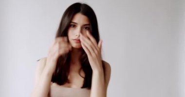 Yüzü sağlıklı, temiz, yeni ciltli beyaz duvarda güzel bir bayan model. Mükemmel genç ten ve güzellik kavramı. Güzellik videosu konsepti, yakın plan portre. Şirin Moda Modeli.