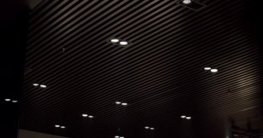 Siyah yuvarlak modern tavan lambası, minimalist iç kısımda, siyah ahşap çizgilerle. Işıklandırma ekipmanlarıyla minimal iç mekan. Modern lamba. Şatafatlı Avize.