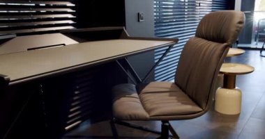 Rahat çalışma odasında minimalist deri koltuklu modern ahşap çalışma masası. Oda palmiyesi dekoru. Minimalist siyah panjurlar. Beauty Interior 'da yatak odası aksesuarı, deri koltuk ve modern masa..