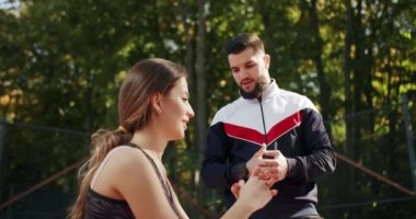 Antrenör erkek, formda kadın egzersizleri yapıyor. Kişisel antrenörle açık hava eğitimi. Sportif erkek ve kadın kalçalarının kaslarını ve kalçalarını güçlendirmek için tek ayak üzerinde hamle yapıyorlar..