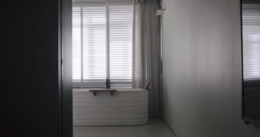 Modern banyonun içinde saydam sürgülü kapı, beyaz ve gri renkli ahşap aksesuarlı minimalist küvet. Modern Minimalist Beyaz Banyo. Beyaz, modern banyo küveti. Lüks Ev.