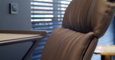 Rahat çalışma odasında minimalist deri koltuklu modern ahşap çalışma masası. Oda palmiyesi dekoru. Minimalist siyah panjurlar. Beauty Interior 'da yatak odası aksesuarı, deri koltuk ve modern masa..