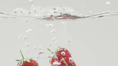 Beyaz arka planda taze çilek suyu içine düştü. Suya düşen taze çilek. Beaty Strawberry suyun içinden geçiyor. Sağlıklı Doğal Vegan Gıda kavramı. Lezzetli Yaz Meyveleri.