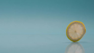 Limon diliminin Slow Motion Macro çekimi mavi arka planda, limonla alkolsüz içecek. Ferahlatıcı limonlu soda ve soğuk yaz içeceği..