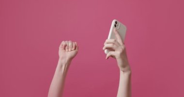 Genç kadın akıllı telefon kullanıyor ve izole edilmiş pembe arka planda Benzerlik sembolünü gösteriyor. Banner ve Metin mesajı için. Her şey iyi görünüyor ve el insan tamam işareti. Başarı jest vücut dili.