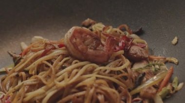 Professional cook frying vegetables with noodles. Asian style food concept composition. New generation of culinary experiences. Tasty asian noodles, Delicious wok noodles shrimp with vegetables.