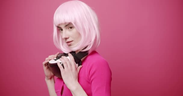 女性は孤立したピンクの背景に仮想現実の眼鏡を使用し 仮想生活の中で追求し 触れます イノベーション テクノロジー ゲーム ライフスタイル エンターテイメントの概念 ピンク色 現代女性 — ストック動画