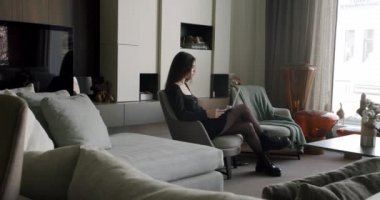 İnternette çalışan dizüstü bilgisayarında daktilo yazan genç bir iş kadını. Modern minimalist oturma odasında, güzel bayan profesyonel kullanıcı bilgisayar teknolojisini kullanarak modern evde online iş yapıyor..