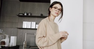 Genç ve güzel bir kadın evdeki modern mutfak odasında kahve ve çay içiyor. Sağlıklı sakin bir bayan minimalist yemek odasında dinleniyor. Evde tek başına stressiz hisset. Kadın evinde dinleniyor..