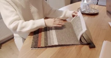 Tekstil galerisindeki renk paletinden kumaş seçen kadın ellerini kapatın. Çok renkli kumaş dokusu arka planı. Kadın mağazadan renk kumaşı seçiyor. Renkli kumaş örnekleri olan tekstil mağazası