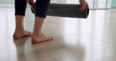 Bir kadın yoga yapmak için bir minder açıyor, sağlıklı yaşam tarzından zevk alıyor spor salonunda egzersiz yapıyor, yoga sınıfında meditasyon yapıyor.