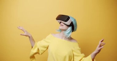 Genç bir kadın oyun oynamak için yenilikçi teknoloji VR gözlükleri kullanıyor ve sanal gerçekliğin 360 VR kulaklığını kullanarak rahatlıyor. Gelecek kavramı, yenilik, teknoloji, oyun, yaşam tarzı.